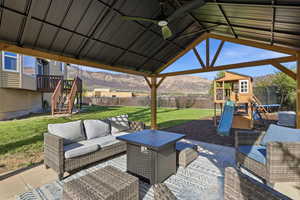 Fenced backyard with a playground, an outdoor hangout area, a mountain view, and a trampoline
