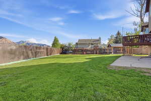 Fenced backyard featuring a trampoline, a mountain view, and a patio