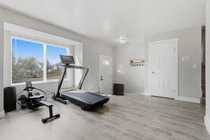 Workout area with light wood-style floors and baseboards