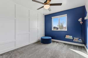 Carpeted empty room featuring a ceiling fan and baseboards