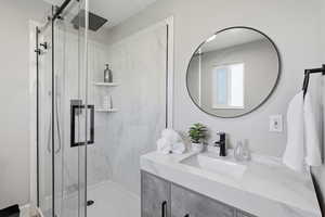 Bathroom with vanity and a marble finish shower