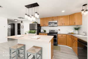 Kitchen featuring a kitchen bar, stainless steel appliances, pendant lighting, butcher block countertops, and new LPV flooring