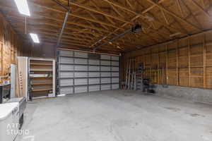 Garage featuring a garage door opener and lots of lighting and storage