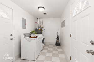 Laundry room featuring light floors, separate washer and dryer, electric panel, and water heater