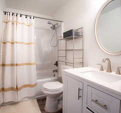 Bathroom with vanity, shower / bathtub combination with curtain, and dark wood finished floors