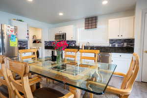 Kitchen featuring decorative backsplash, white cabinets, washer / dryer, stainless steel appliances, and recessed lighting