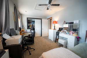 Carpeted bedroom featuring a desk, a closet, and ceiling fan