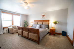 Carpeted bedroom with ceiling fan and baseboards