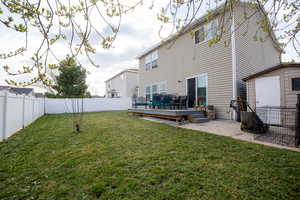 Rear view of property featuring a wooden deck, a fenced backyard, and a storage shed