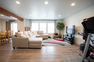 Living room with light wood-style floors, recessed lighting, and beamed ceiling