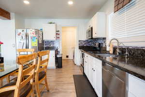 Kitchen with stainless steel appliances, white cabinetry, dark stone countertops, tasteful backsplash, and recessed lighting