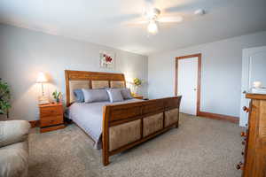 Carpeted bedroom with a ceiling fan and baseboards