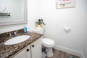 Half bath featuring vanity and dark wood-type flooring
