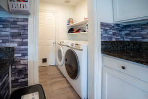 Laundry room with light wood-type flooring and washing machine and dryer