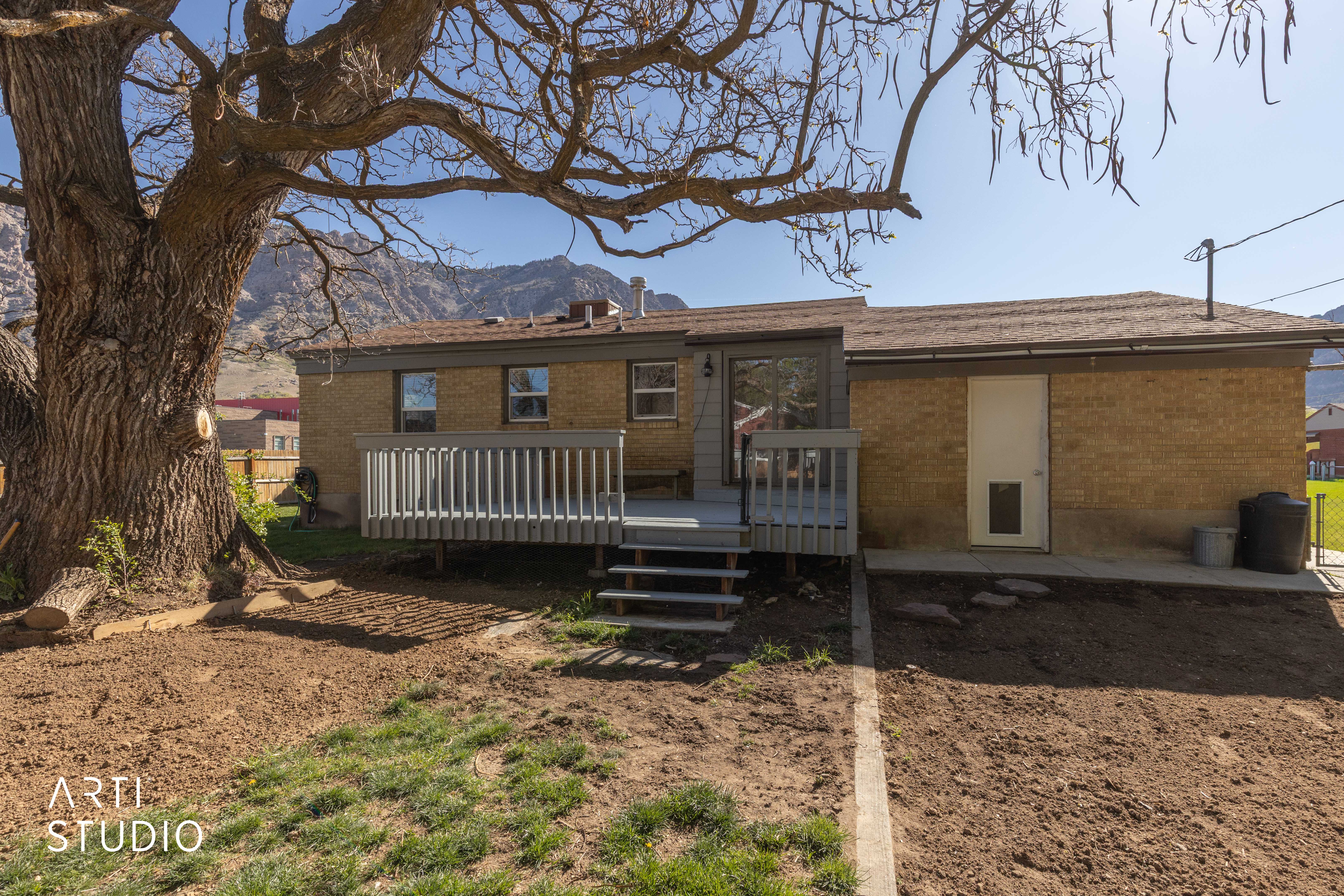 Rear view of property featuring brick siding and a deck with mountain in background