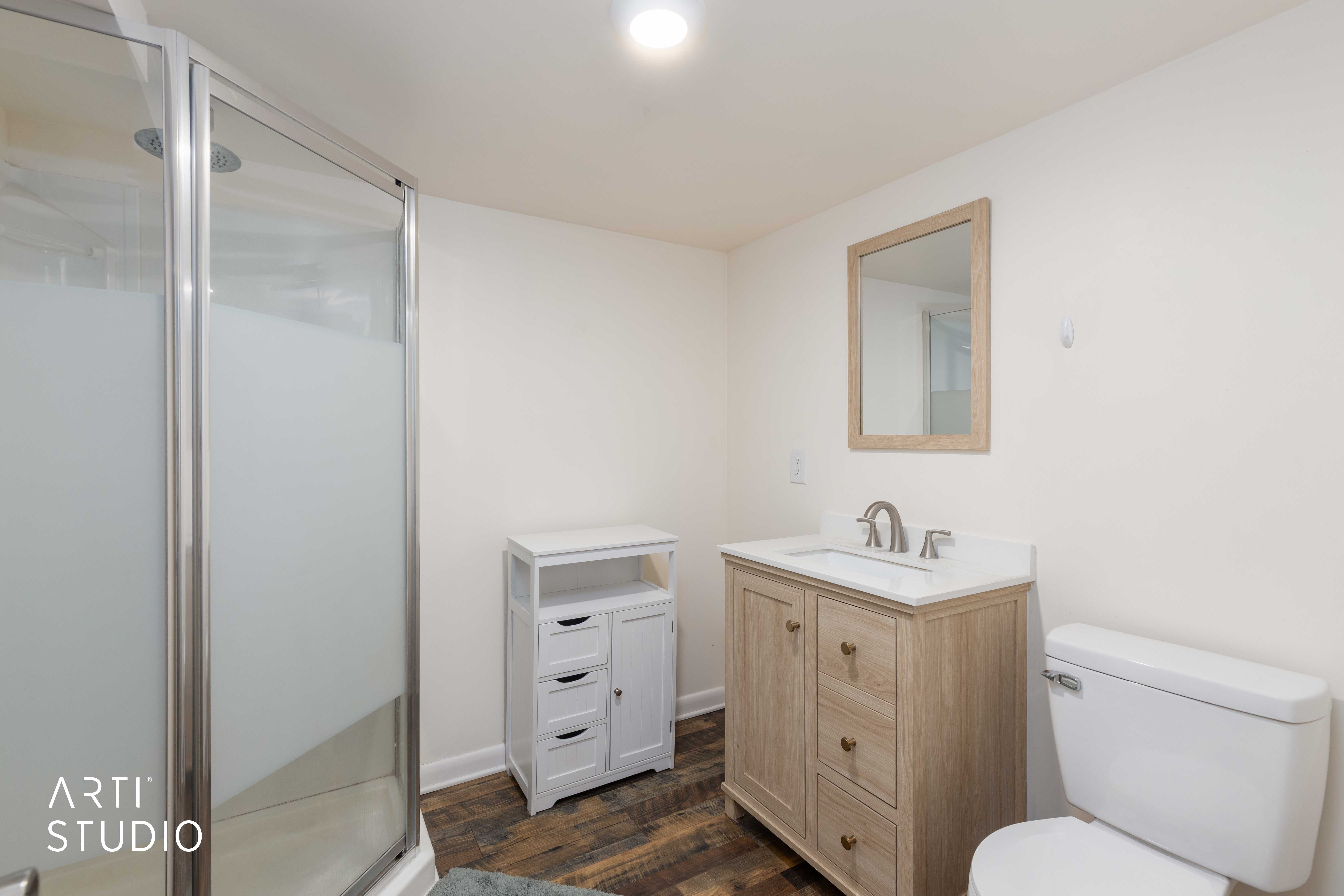 Downstairs 3/4 bath, with vanity, a stall shower, and dark wood-style flooring