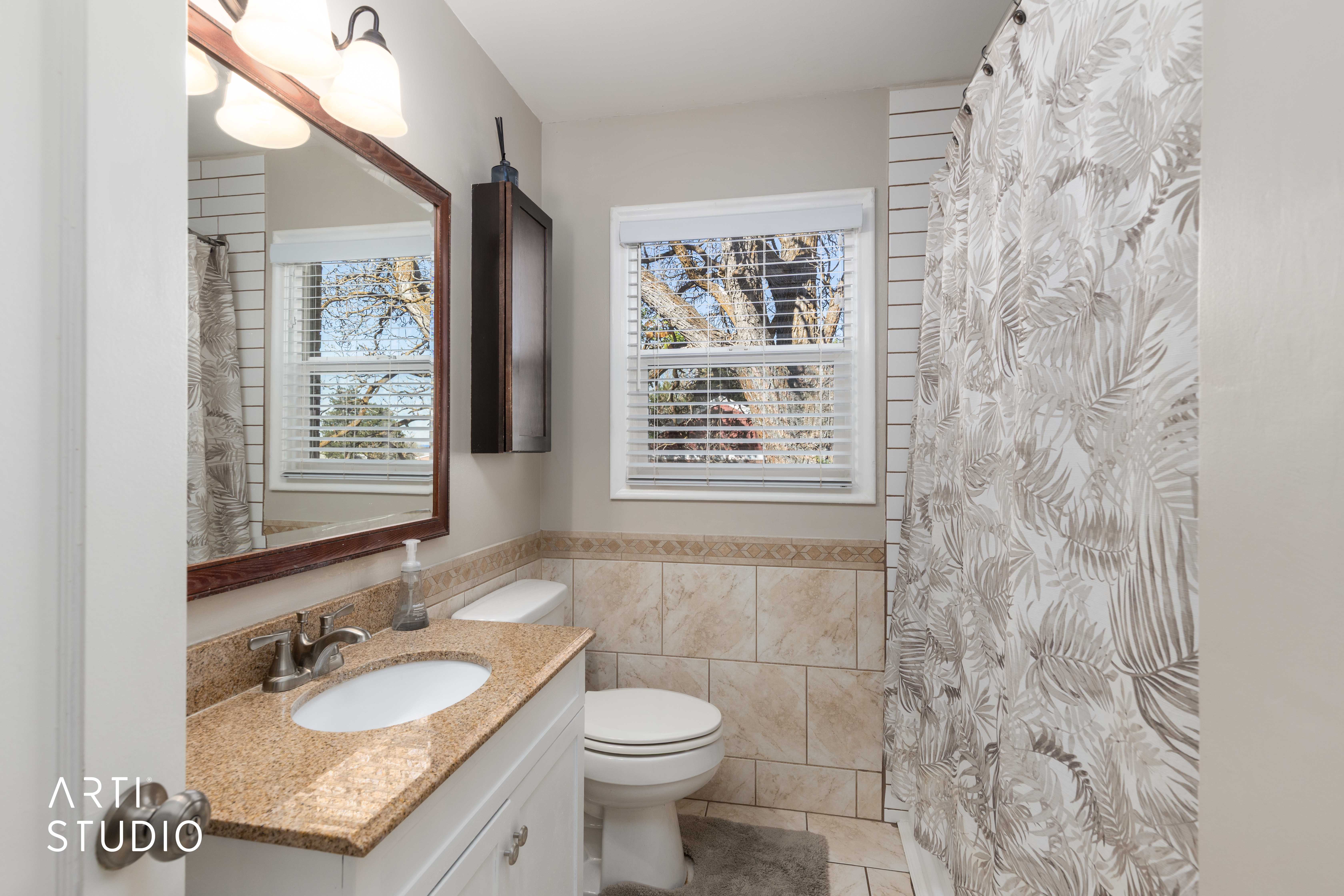 Full bath with a shower with shower curtain, vanity, light tile patterned flooring, tile walls, and wainscoting