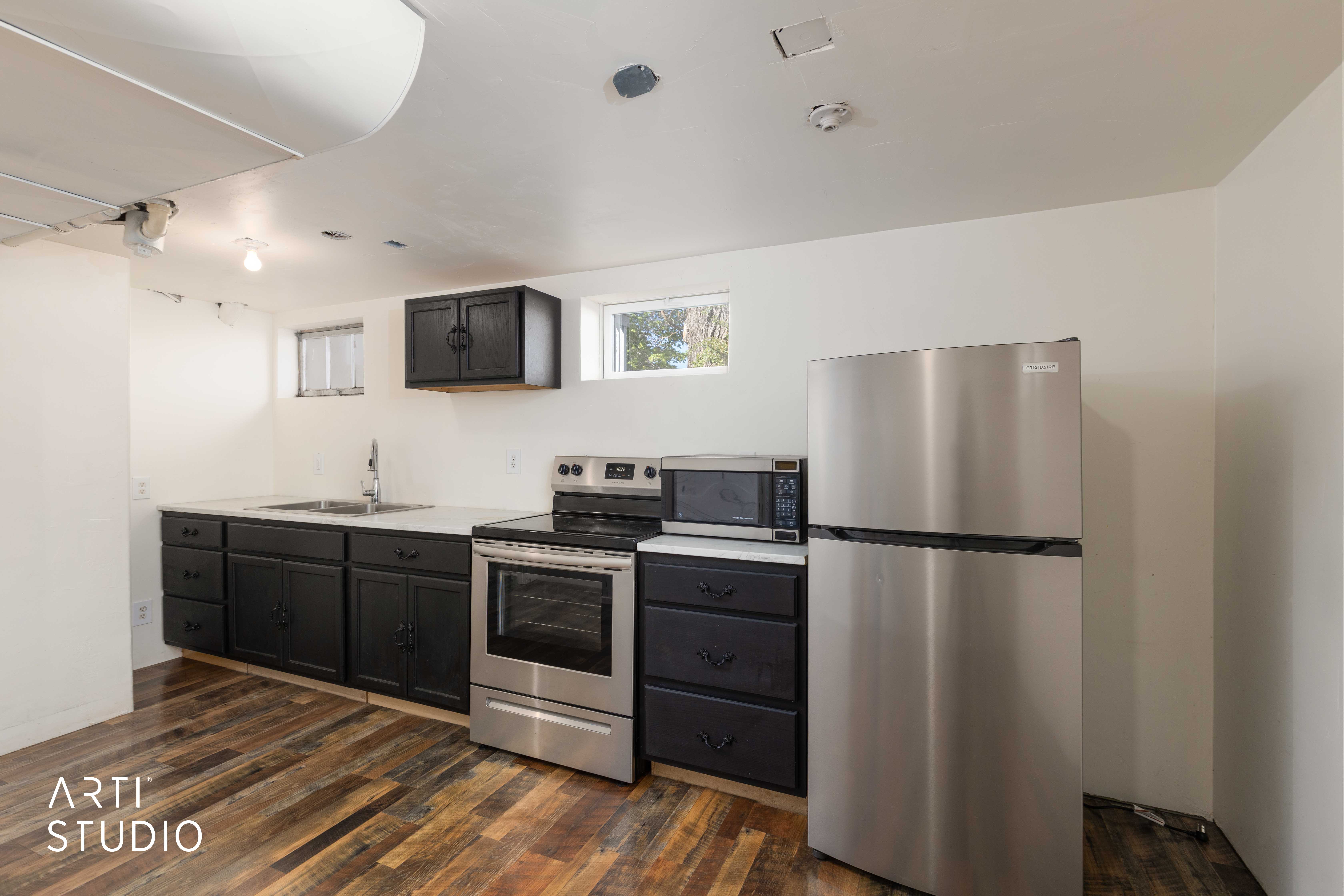 Kitchen featuring stainless steel appliances, light countertops, and dark wood-style flooring