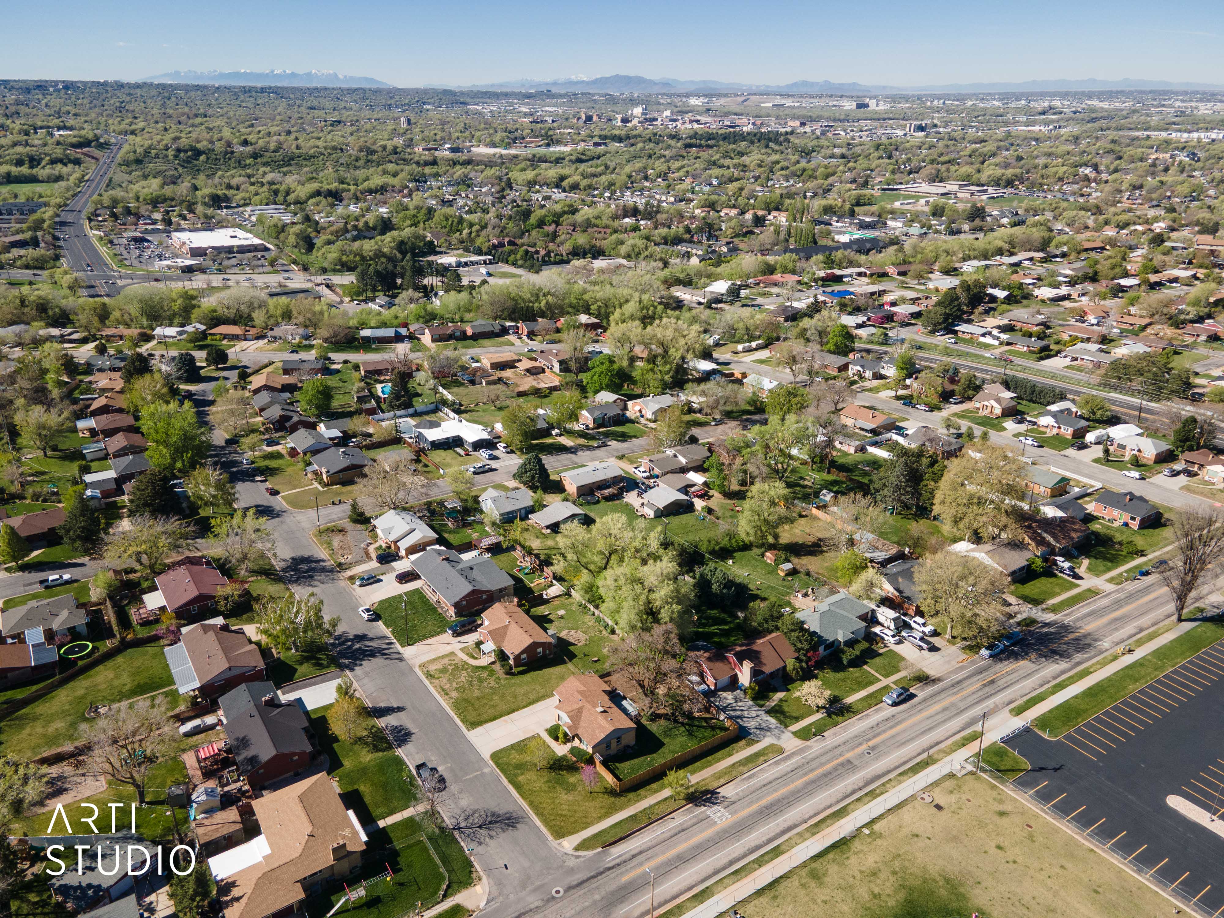 Aerial view of property and surrounding area featuring a mountainous background and nearby suburban area