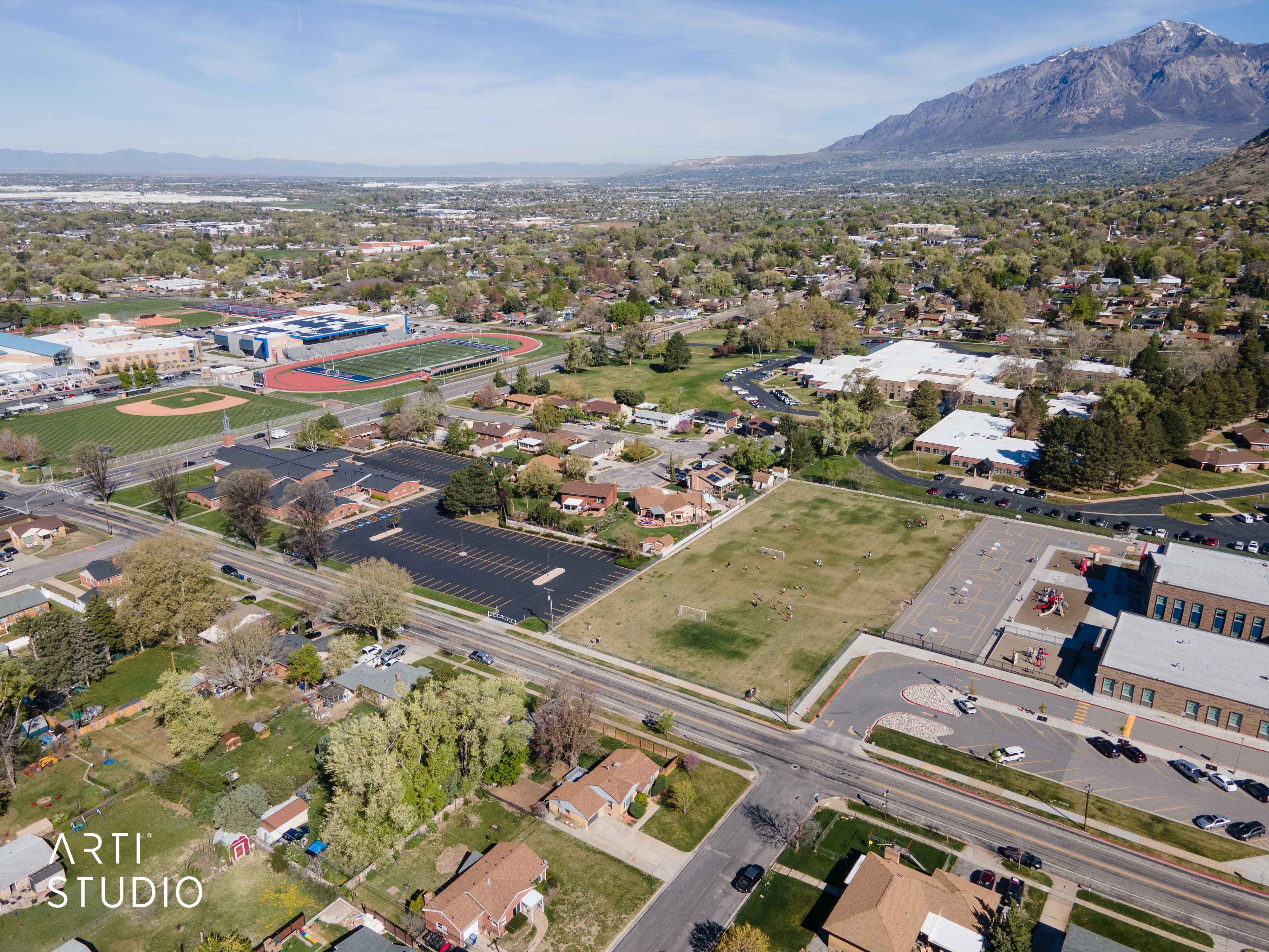 Aerial view of property and surrounding area featuring mountains and nearby suburban area