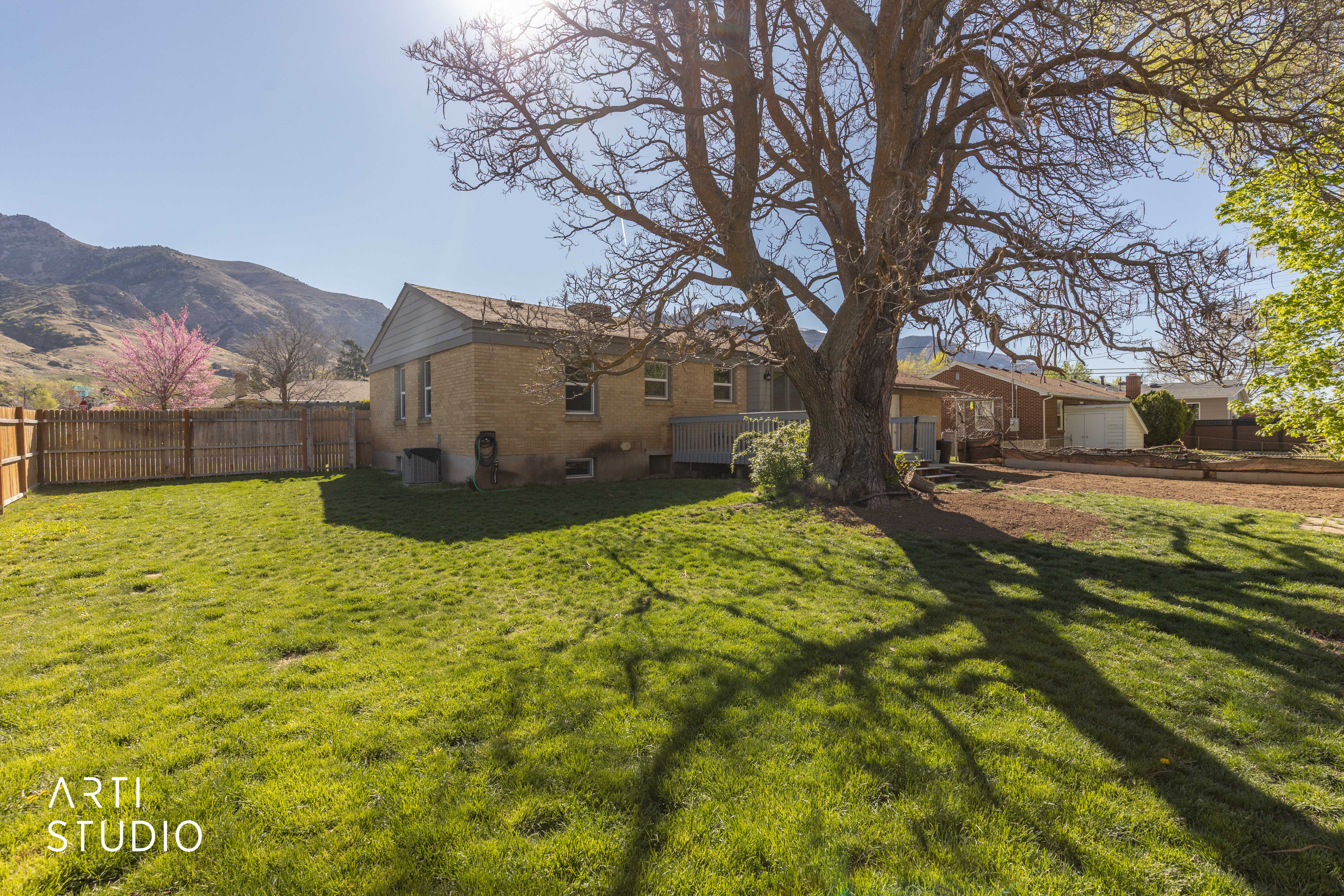 Back of house featuring brick siding, a chimney, a deck with mountain view, and a fenced backyard