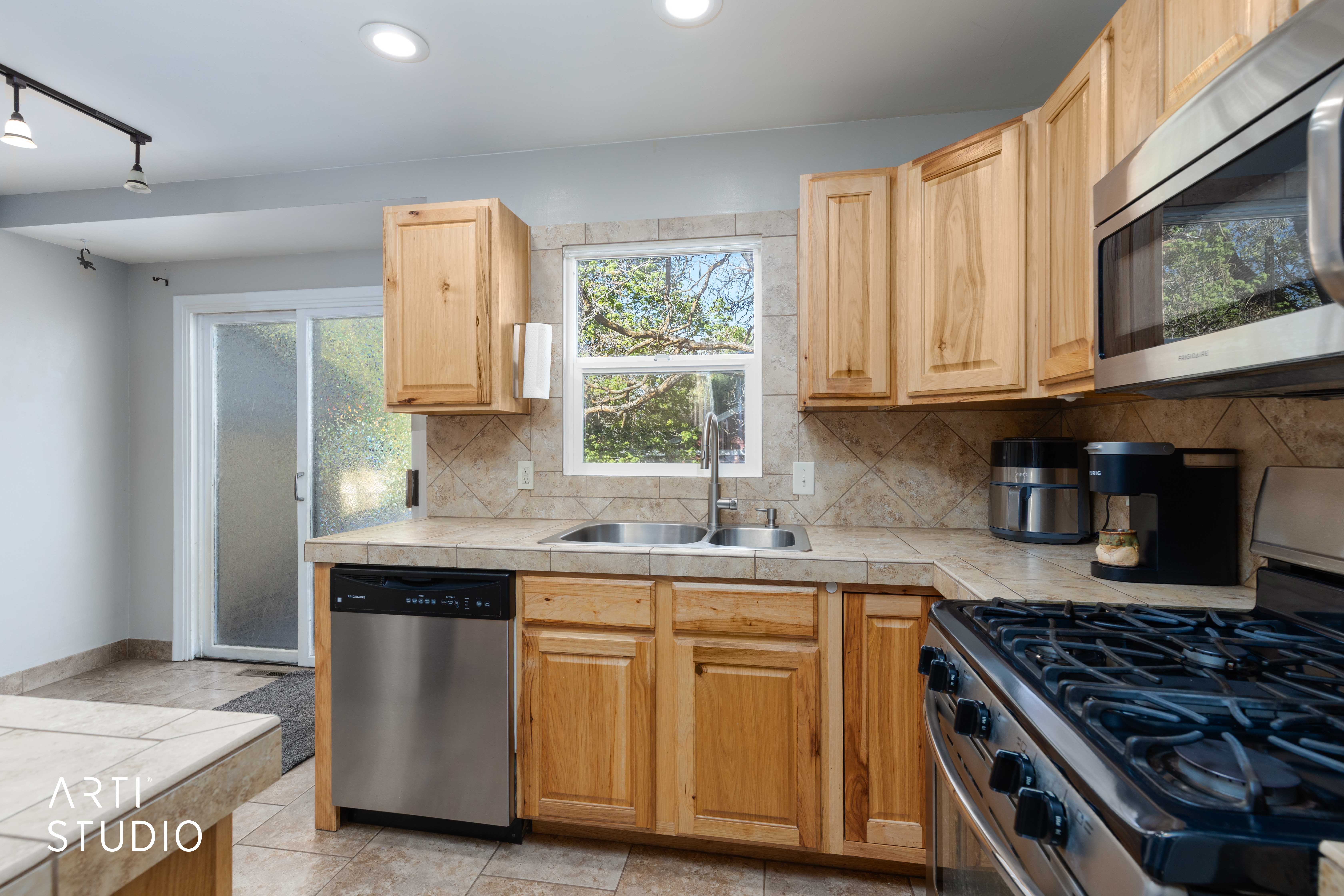 Kitchen with stainless steel appliances, light wood finish cabinetry, tasteful backsplash, tile counters, and track lighting