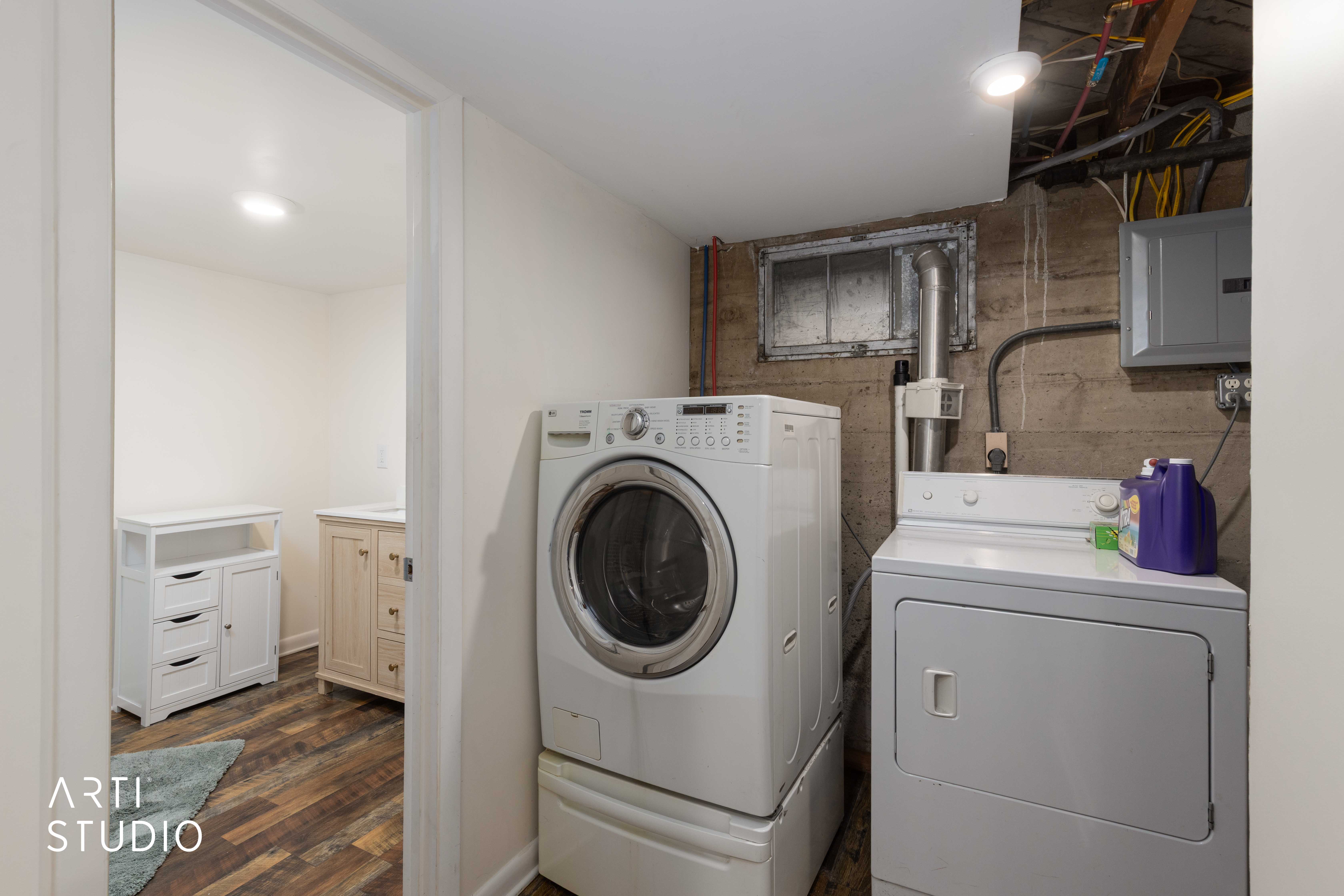 Laundry area featuring electric panel, washer and dryer, and dark wood-style flooring