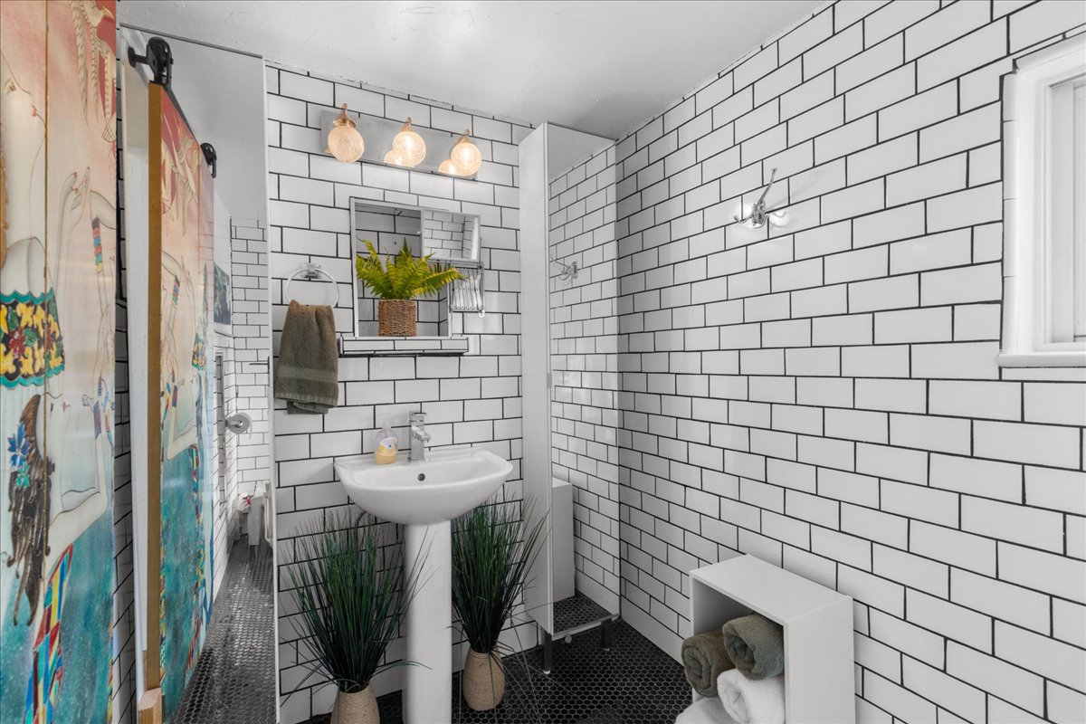 Bathroom with tile walls, tile patterned floors, and a shower