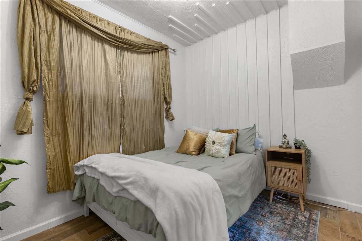 Bedroom with a textured wall and wood finished floors