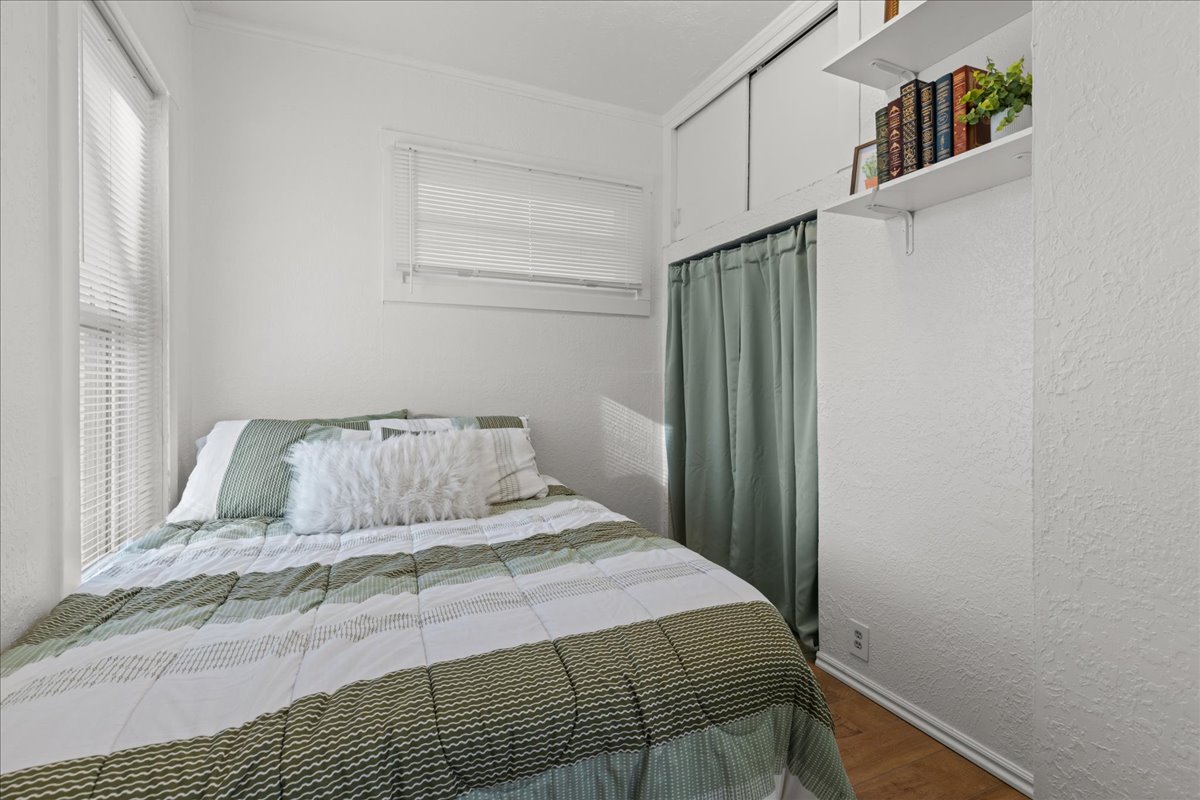 Bedroom featuring wood finished floors, a textured wall, and ornamental molding