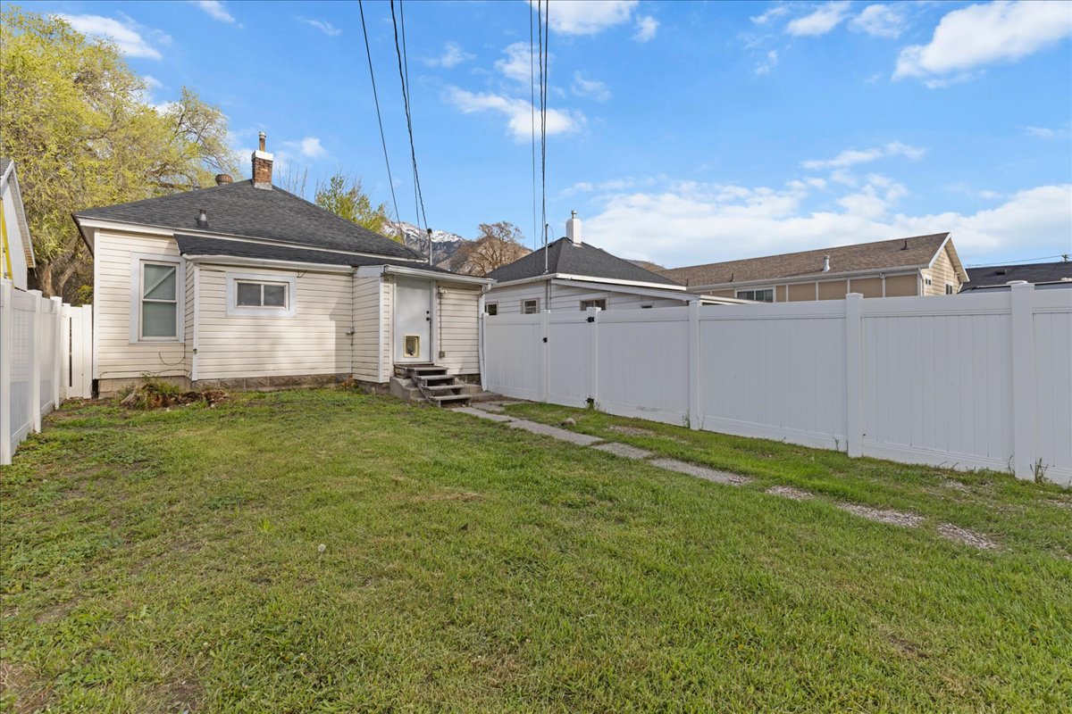 Back of property featuring a fenced backyard, entry steps, and a chimney