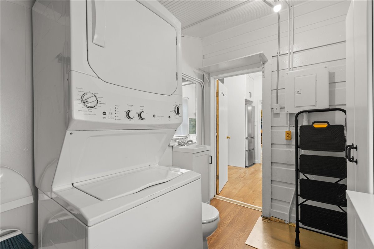 Laundry area featuring stacked washer and dryer and light wood-style floors