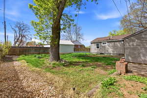 Fenced backyard featuring a trampoline and an outbuilding