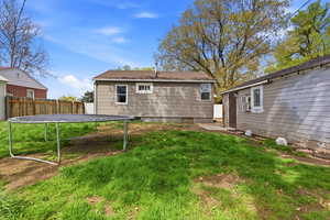 Rear view of house with a trampoline and a patio area