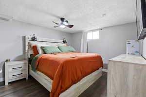 Bedroom featuring dark wood-style floors, ceiling fan, and a textured ceiling