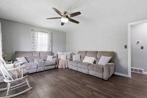 Living area featuring dark wood-style floors, ceiling fan, and a textured ceiling