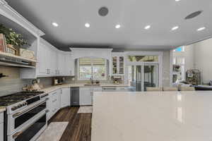 Kitchen featuring double oven range, white cabinetry, dark wood-style flooring, glass fronted cabinets, and recessed lighting
