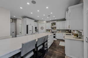 Kitchen featuring a kitchen bar, white cabinetry, recessed lighting, light stone counters, and high quality appliances