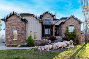Craftsman-style home featuring board and batten siding, stone siding, and a front yard