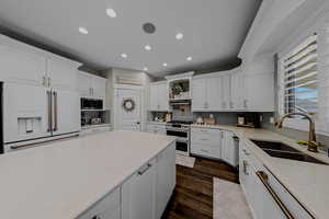 Kitchen with stainless steel appliances, white cabinets, decorative backsplash, recessed lighting, and dark wood-type flooring