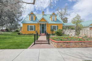 View of front facade featuring a chimney, a metal roof, and a front yard