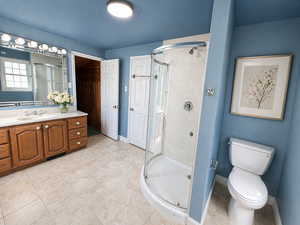 Full bath with vanity, a shower stall, and light tile patterned floors