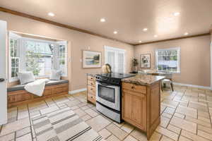 Kitchen with stainless steel electric range, a center island, recessed lighting, dark stone counters, and ornamental molding