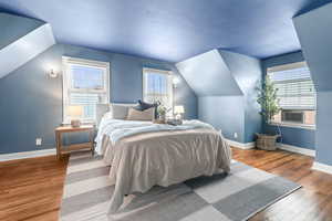Bedroom with wood-type flooring and vaulted ceiling