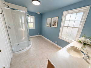 Bathroom with vanity, a shower stall, and light tile patterned floors