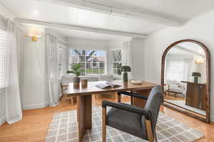 Dining space featuring beamed ceiling, light wood-type flooring, arched walkways, and crown molding