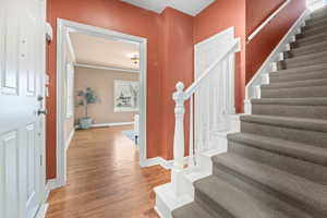 Foyer entrance with light wood-type flooring and ornamental molding