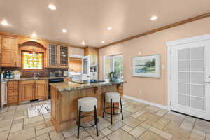 Kitchen with glass fronted cabinets, a breakfast bar area, dark stone countertops, recessed lighting, and a center island