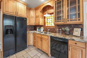 Kitchen featuring black appliances, glass fronted cabinets, light stone counters, decorative backsplash, and a textured ceiling