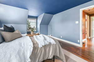 Bedroom with wood finished floors and lofted ceiling